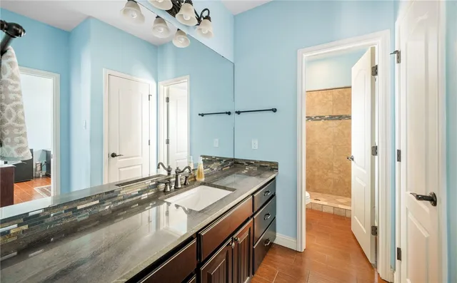 a bathroom with a granite countertop sink a mirror and a shower