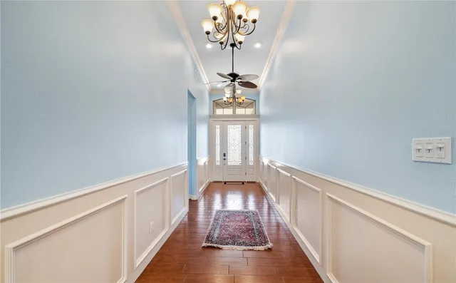 a view of a hallway with wooden floor and chandelier
