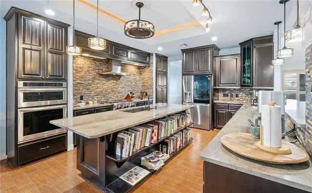 a kitchen with stainless steel appliances kitchen island granite countertop a table chairs in it and wooden floors