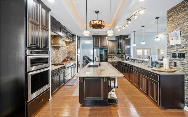 a kitchen with stainless steel appliances granite countertop a sink and a refrigerator