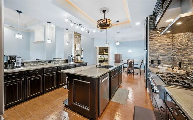 a kitchen with stainless steel appliances granite countertop a stove a sink dishwasher and a refrigerator with wooden floor