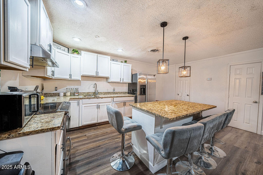 4233 North 68th Avenue Phoenix, AZ 85033 - Photo 3 of 11 a kitchen with granite countertop a table chairs a sink dishwasher stove and cabinets with wooden floor