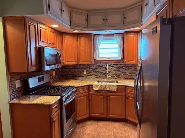 a kitchen with stainless steel appliances granite countertop a stove a sink and a refrigerator