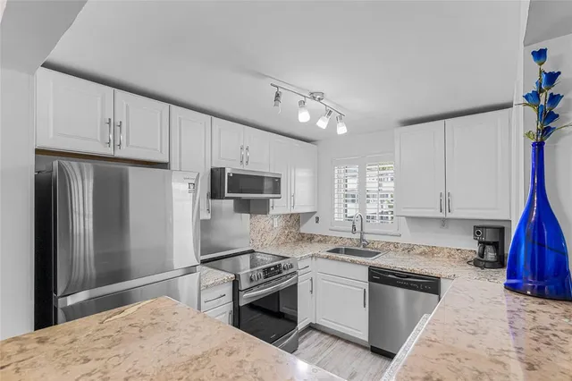 a kitchen with granite countertop a refrigerator stove and sink