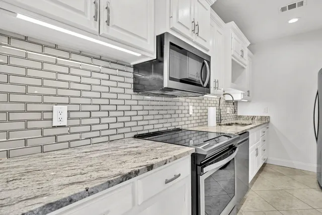 a kitchen with granite countertop cabinets stainless steel appliances and a counter space