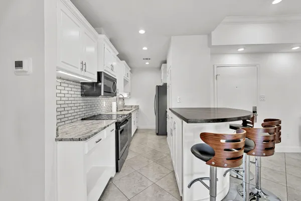 a kitchen with stainless steel appliances granite countertop a stove a sink a refrigerator and a microwave