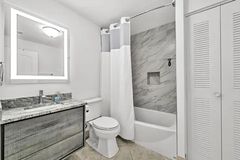 a bathroom with a granite countertop sink toilet and shower
