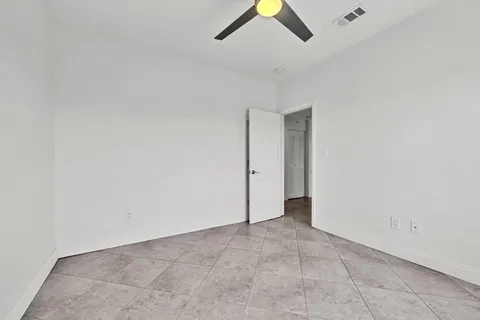 an empty room with a ceiling fan and window