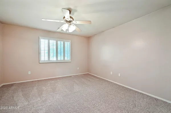 an empty room with windows and chandelier fan