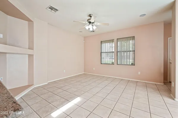 a view of an empty room with window and chandelier fan
