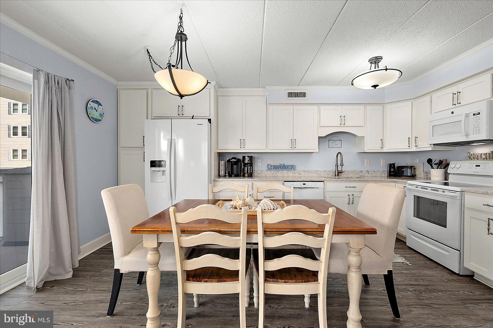 4 46th Street, Unit 101 Ocean City, MD 21842 - Photo 11 of 27 a kitchen with stainless steel appliances kitchen island granite countertop a dining table chairs and sink
