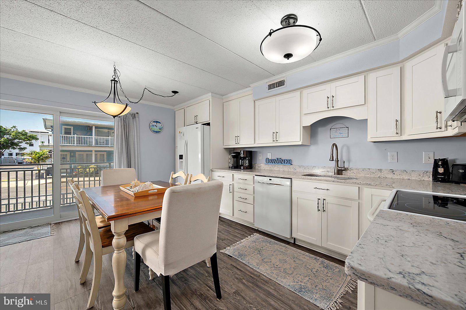 4 46th Street, Unit 101 Ocean City, MD 21842 - Photo 7 of 27 a kitchen with stainless steel appliances granite countertop a stove a sink dishwasher a dining table and chairs with wooden floor