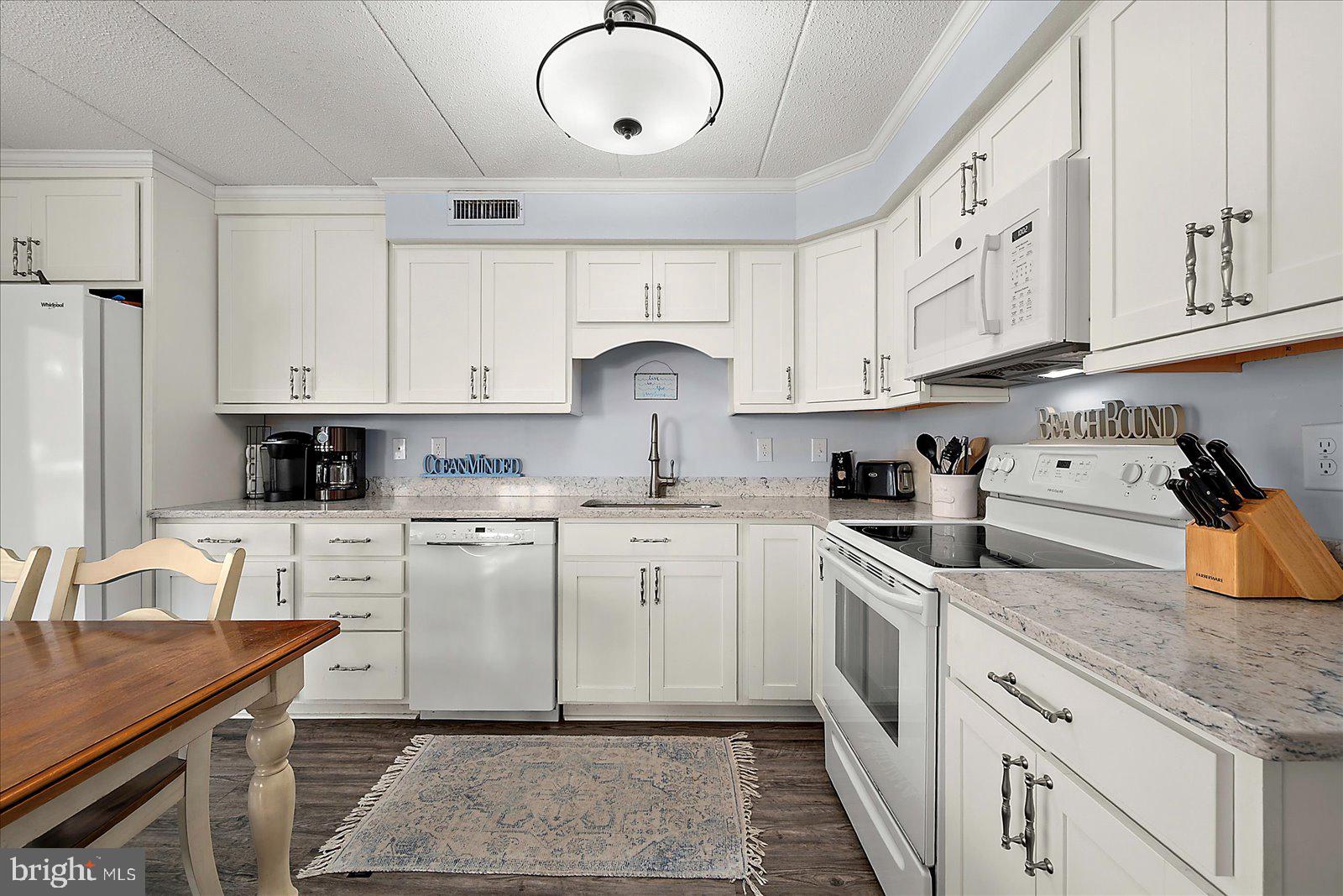 4 46th Street, Unit 101 Ocean City, MD 21842 - Photo 8 of 27 a kitchen with stainless steel appliances granite countertop white cabinets sink and stove