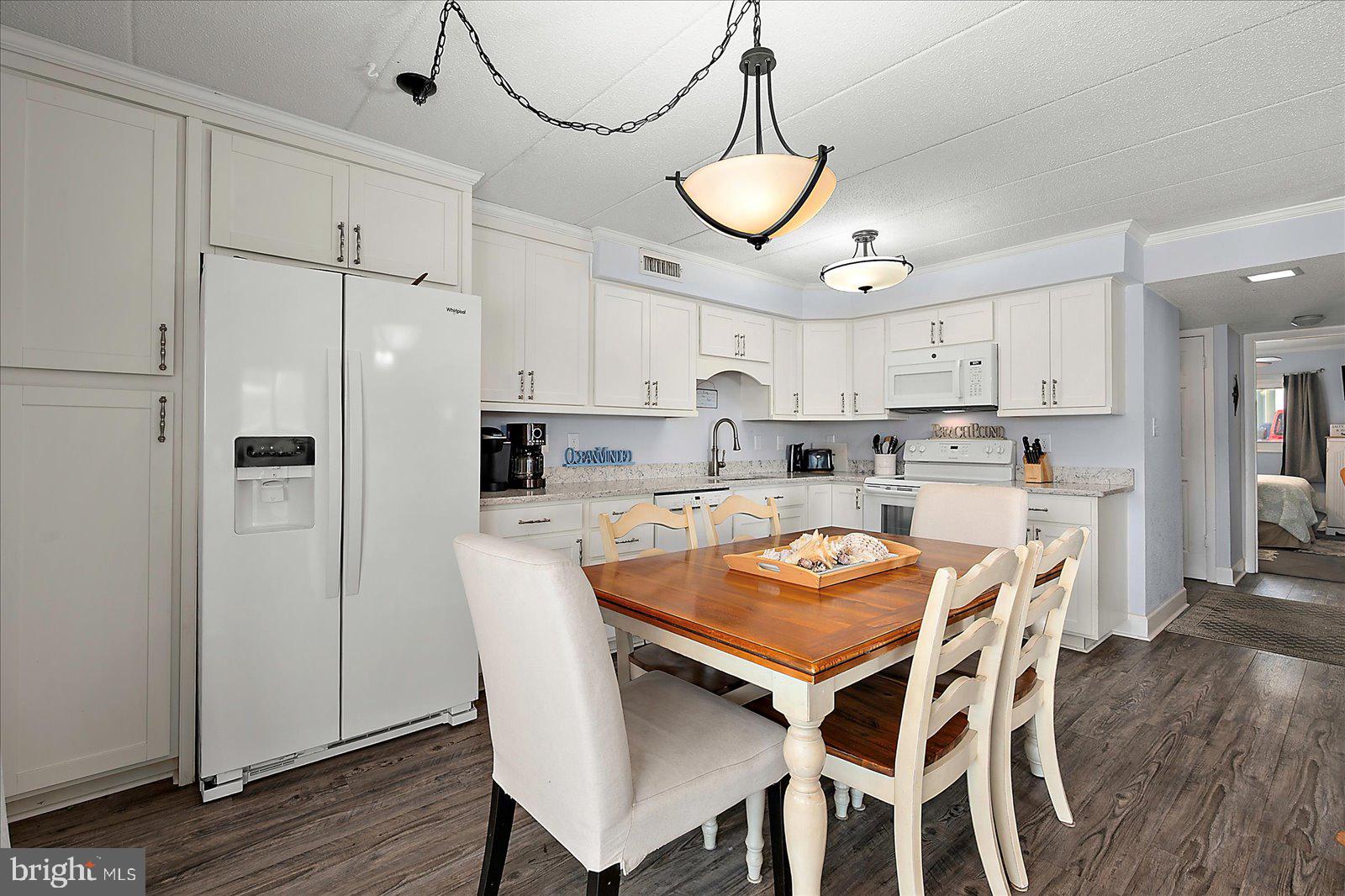 4 46th Street, Unit 101 Ocean City, MD 21842 - Photo 10 of 27 a kitchen with stainless steel appliances granite countertop a dining table chairs and white cabinets