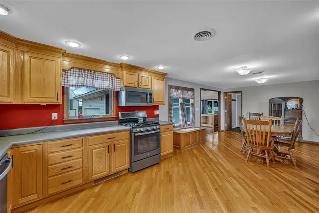 an empty room with wooden floor chandelier fan and windows
