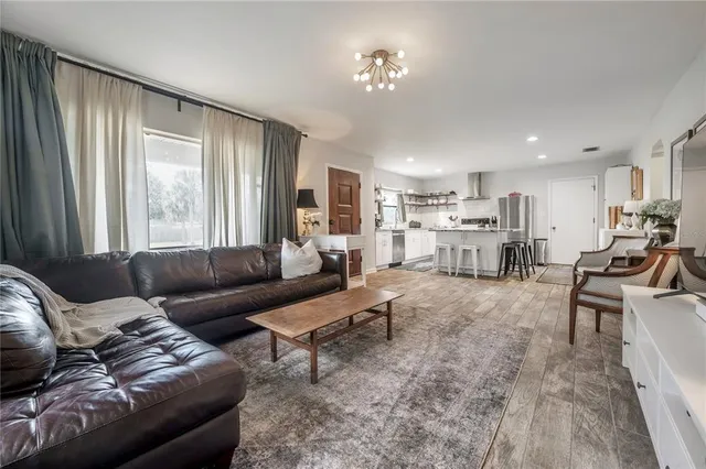 a living room with furniture a flat screen tv and kitchen view