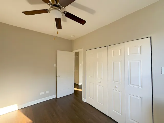 an empty room with wooden floor closet and fan