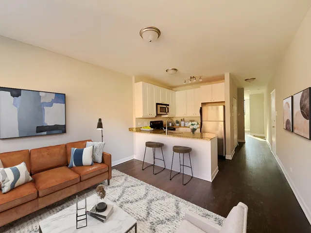 a living room with stainless steel appliances kitchen island granite countertop a couch and white cabinets