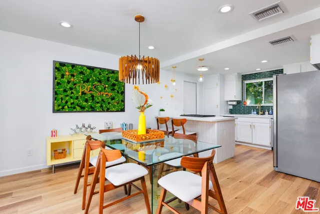 a view of a kitchen with kitchen island stainless steel appliances wooden floor dining table and chair