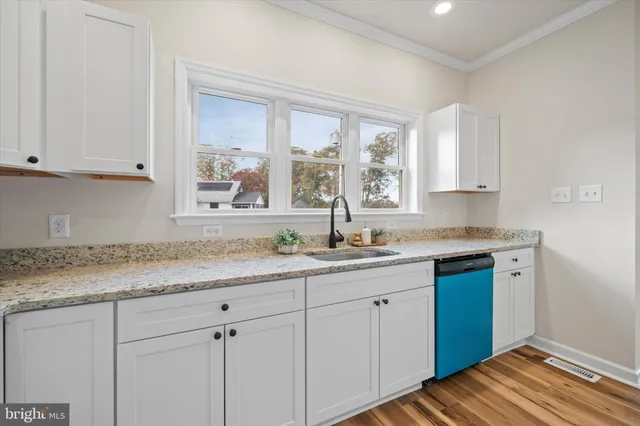 a view of a kitchen and an empty room with wooden floor