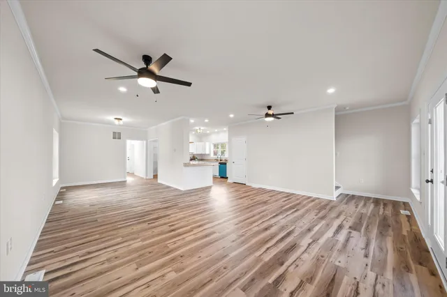 a view of empty room with wooden floor and ceiling fan