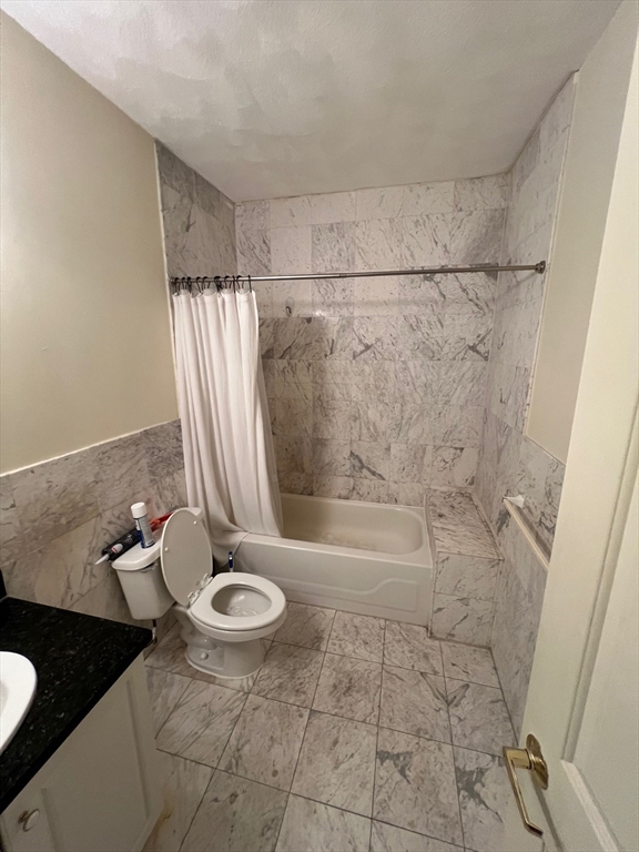 373 Highland Avenue, Unit 308 Somerville, MA 02144 - Photo 6 of 9 a bathroom with a granite countertop sink a toilet and a bathtub