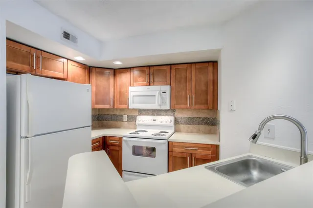a kitchen with a refrigerator sink and wooden cabinets