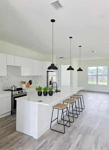 a kitchen with stainless steel appliances granite countertop a stove a sink dishwasher and a wooden floor