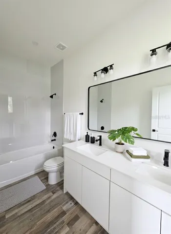 a bathroom with a double vanity sink toilet mirror and bathtub