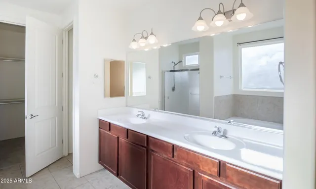 a bathroom with double vanity sinks a vanity a lamp and a mirror
