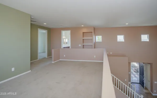 a view of an empty room with wooden floor and stairs