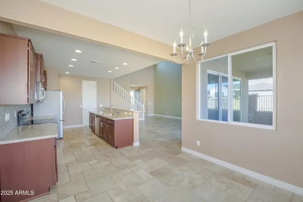 a large kitchen with kitchen island a chandelier stainless steel appliances a sink and a counter top space