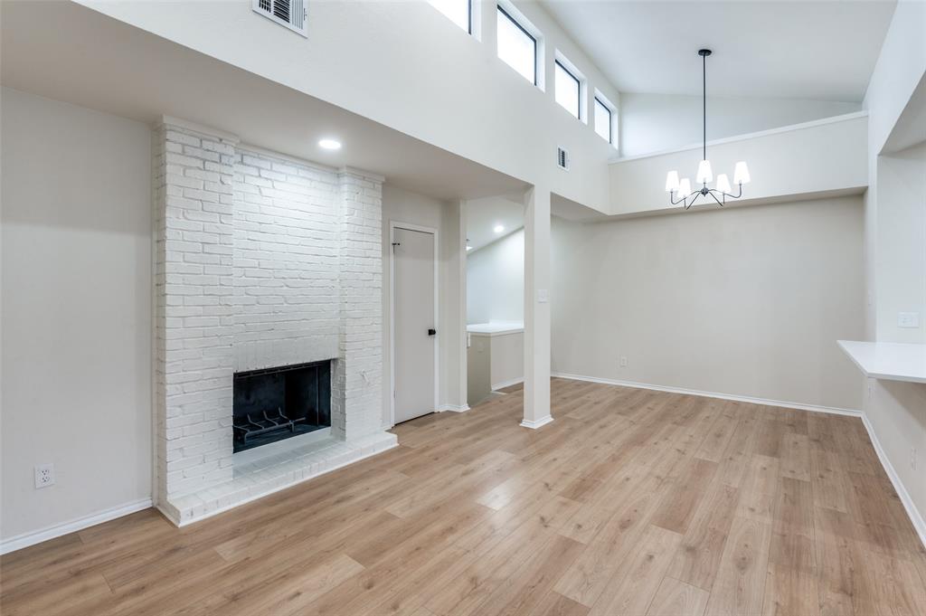 17490 Meandering Way, Unit 2202 Dallas, TX 75252 - Photo 3 of 24 Spacious room featuring vaulted ceilings, wood-finish flooring, and a white brick fireplace