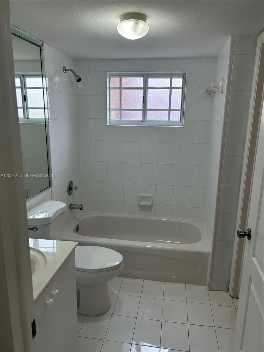 10919 West Okeechobee Road, Unit 101 Hialeah Gardens, FL 33018 - Photo 18 of 21 a bathroom with a granite countertop toilet a sink and bathtub