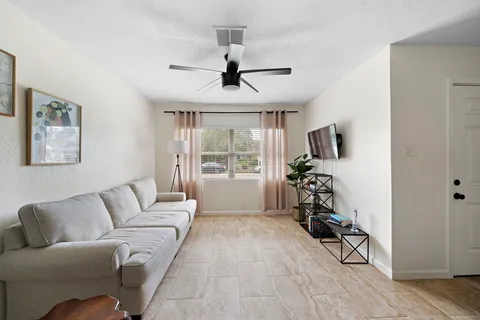 a living room with furniture a flat screen tv and a window