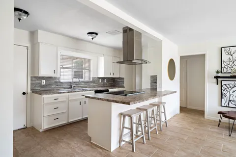 a kitchen with stainless steel appliances kitchen island granite countertop a stove a sink and a refrigerator