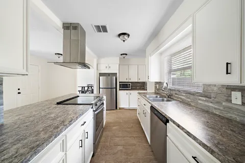 a kitchen with granite countertop a sink stove and cabinets