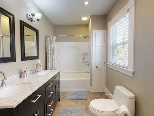 a bathroom with a double vanity sink toilet mirror and bathtub