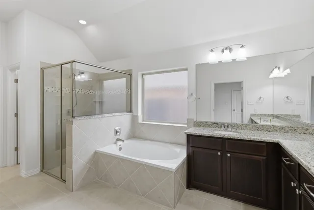 a bathroom with a granite countertop bathtub a sink and a mirror