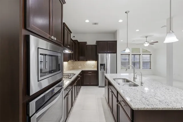 a kitchen with stainless steel appliances granite countertop a sink a stove and a refrigerator