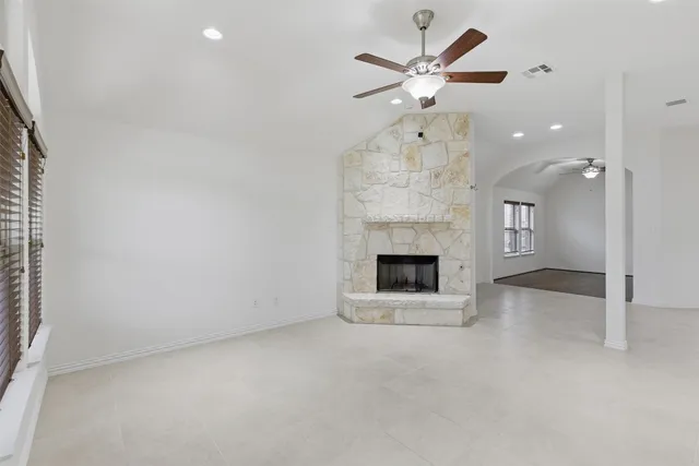 an empty room with a fireplace and a ceiling fan