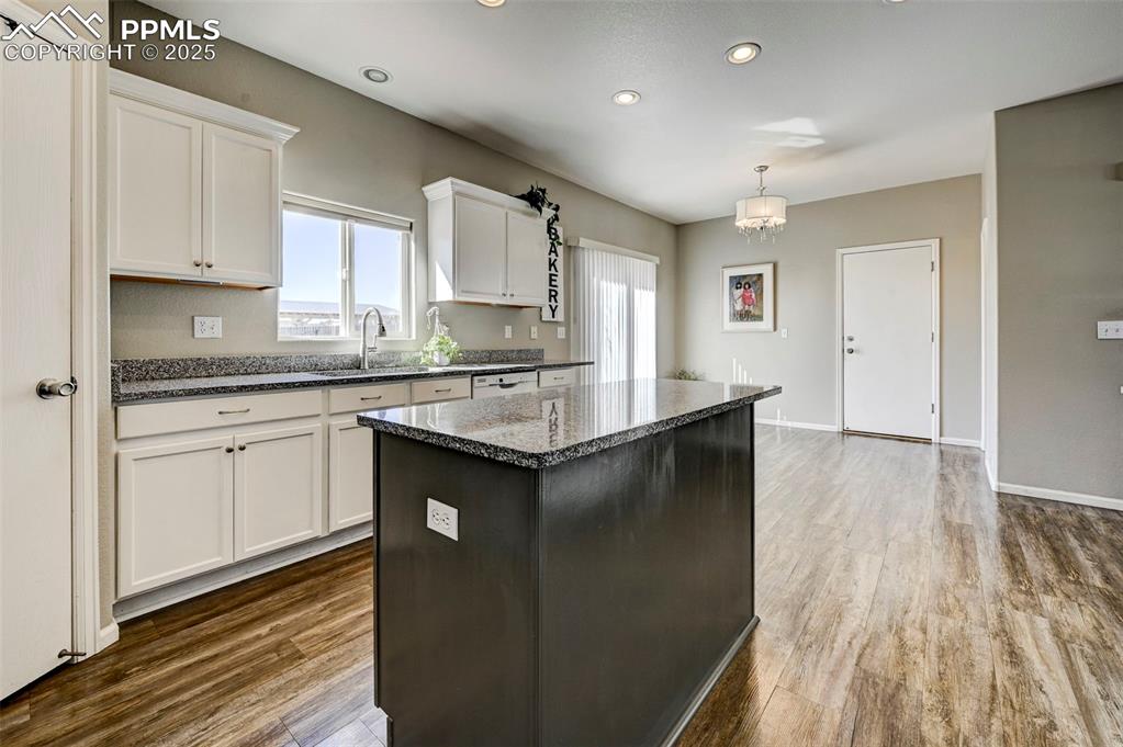 9332 Bethpage Road Peyton, CO 80831 - Photo 7 of 32 a kitchen with a sink dishwasher a stove and white cabinets with wooden floor
