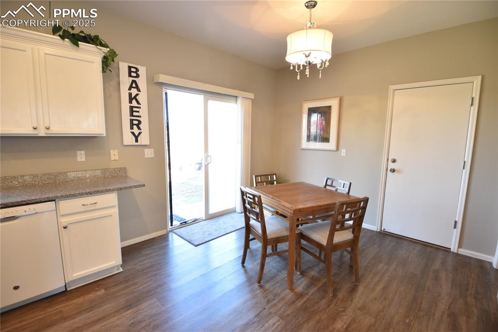 9332 Bethpage Road Peyton, CO 80831 - Photo 10 of 32 a dining room with wooden floor a chandelier a wooden table and chairs