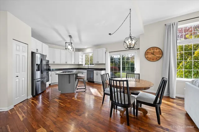 a kitchen with stainless steel appliances granite countertop a refrigerator a sink dishwasher a stove and white countertops with wooden floor