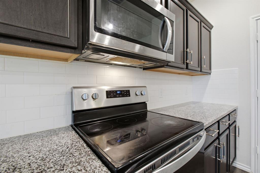 1328 Broaddus Road Forney, TX 75126 - Photo 14 of 31 Kitchen with dark wood cabinetry, light speckled countertops, a stainless steel microwave, a stainless steel range, and a white subway tile backsplash