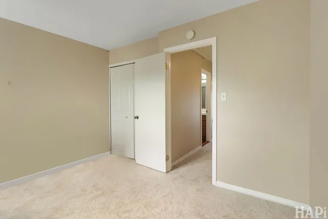 a view of an empty room with closet and mirror
