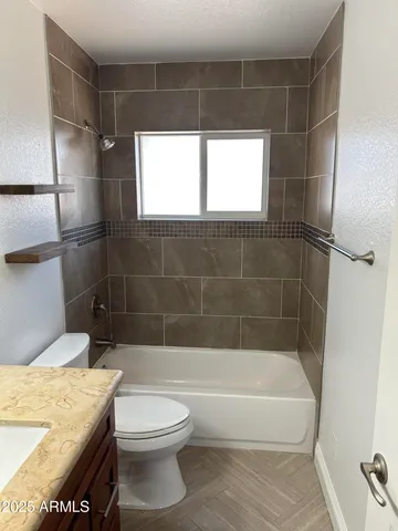 a bathroom with a granite countertop bathtub shower sink vanity and toilet