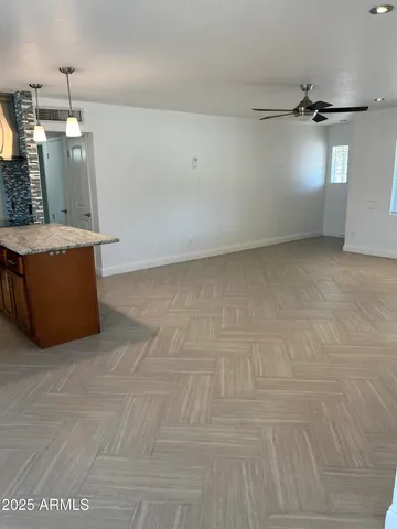 an empty room with chandelier fan and windows