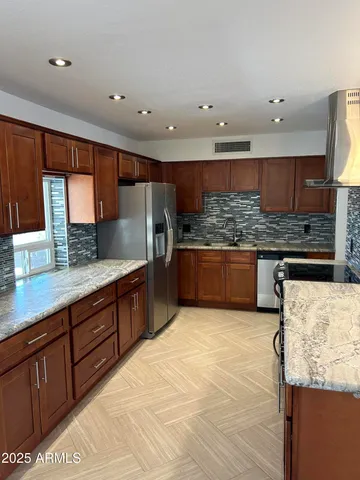 a large kitchen with stainless steel appliances kitchen island granite countertop a large counter top and a stove