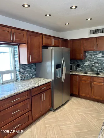 a kitchen with stainless steel appliances granite countertop a refrigerator and a sink